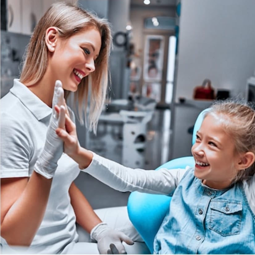 Kinderzahnmedizin: Zahnärztin und kleine Patientin geben sich High Five